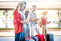 Family looking at phones standing with luggage in sunny indoor space