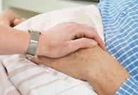Hands being held in hospital bed