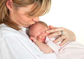Mother holding and kissing newborn baby