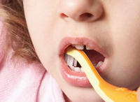 Toddler having the chewing surfaces of her teeth cleaned by an adult